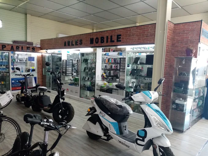 Espace intérieur avec l’enseigne ARLES MOBILE, des vitrines, un scooter blanc et plusieurs deux-roues